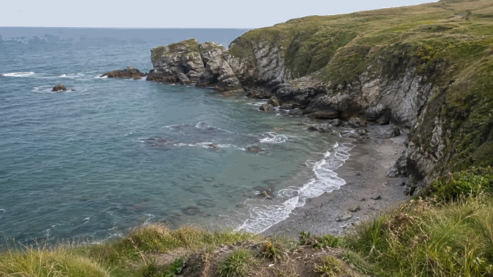 A painterly view from grassy coastal cliffs across blue-green water to waves washing onto a sheltered pebble shore.